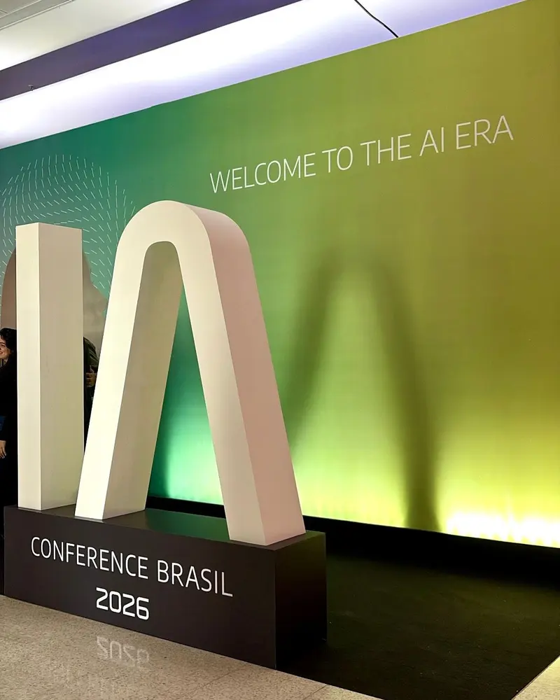 Letreiro gigante “IA” da IA Conference Brasil 2026 diante de um painel verde com a frase “Welcome to the AI era”