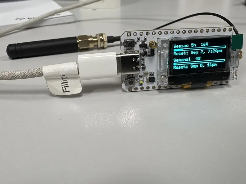 Placa ESP32 com antena LoRa e display OLED mostrando percentuais de uso de sessão e semanal